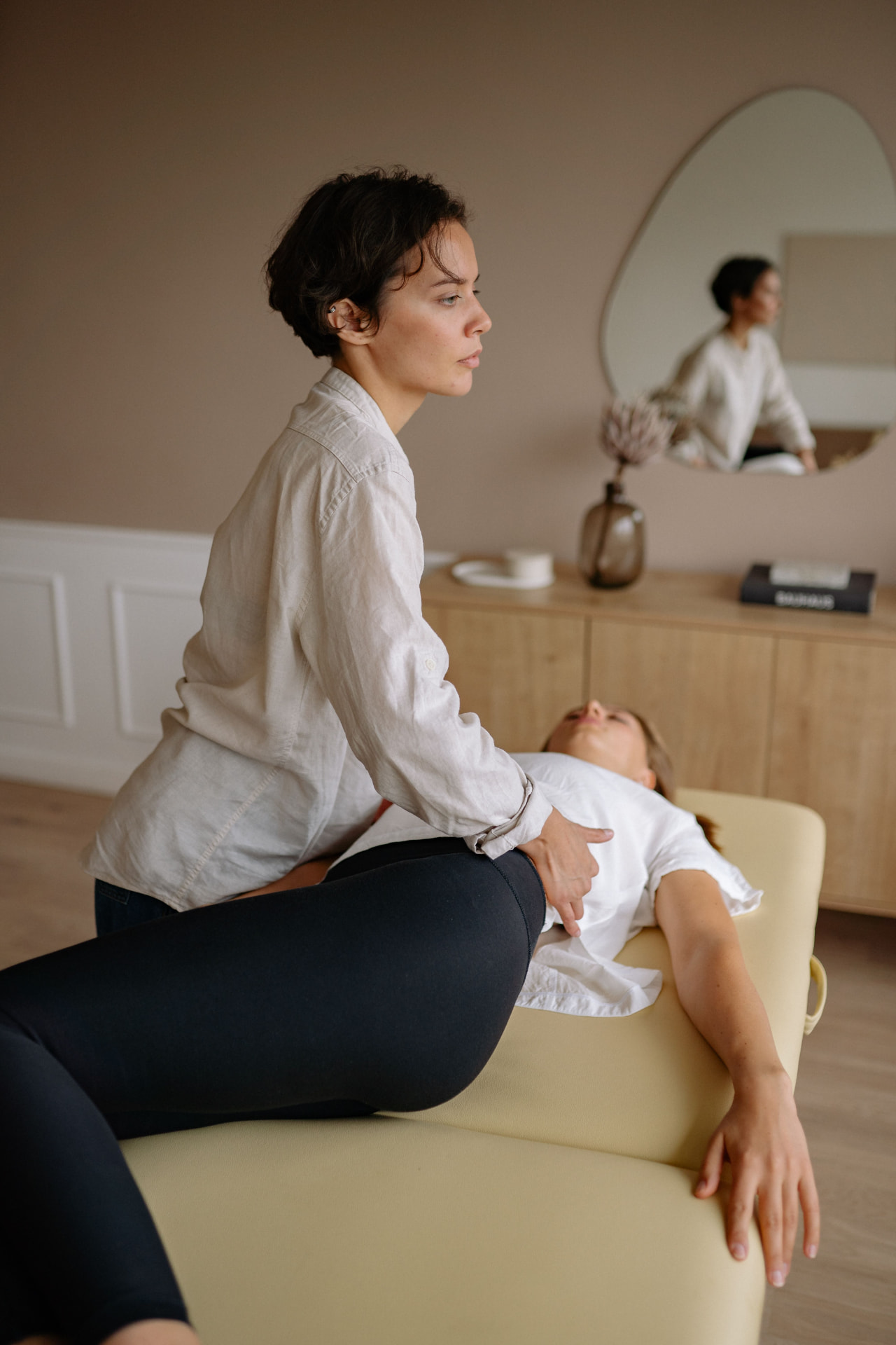 Somatic pelvic and lower back release session on a massage table in soft warm light