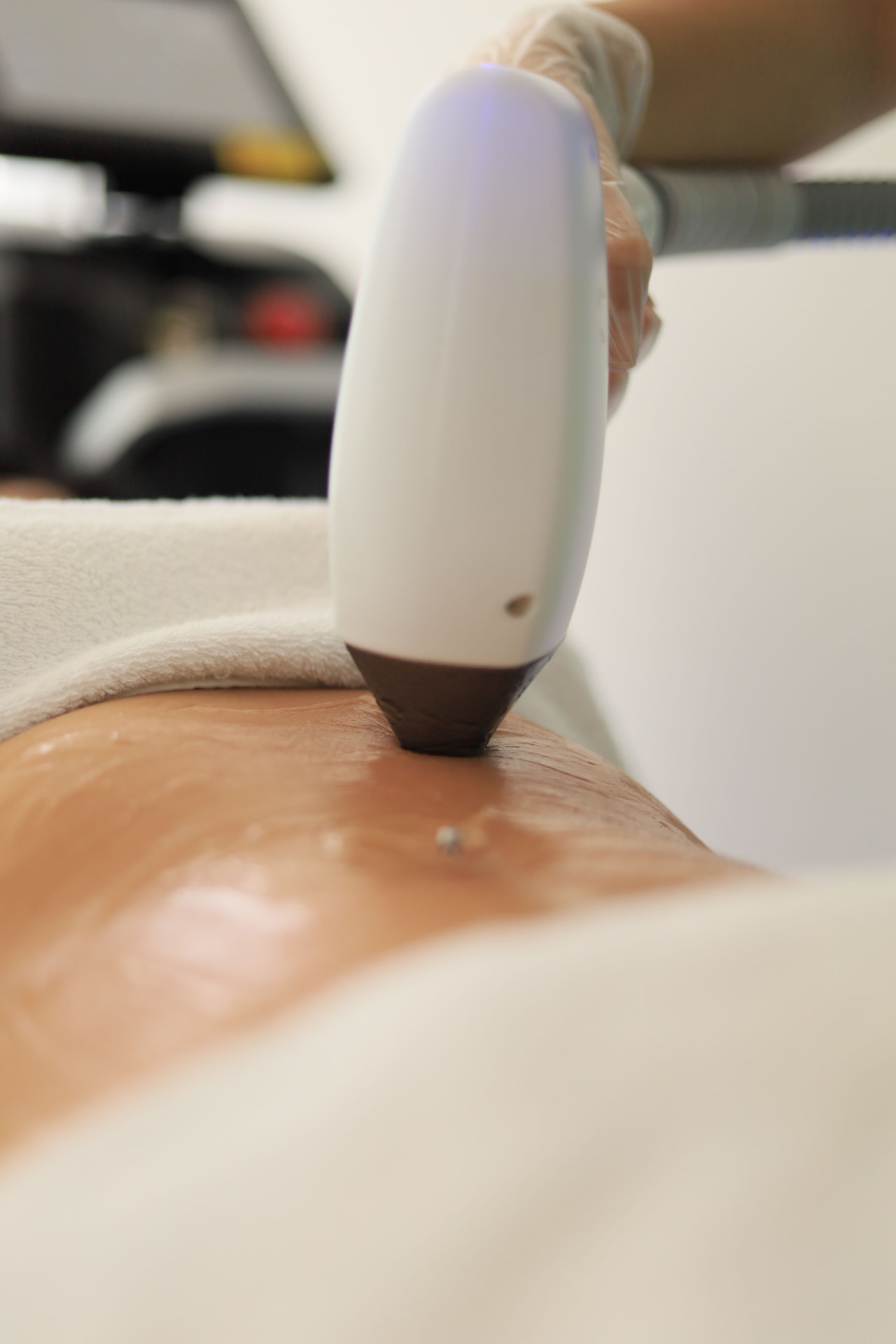 Close-up of a laser lipo contouring treatment being applied in warm studio light